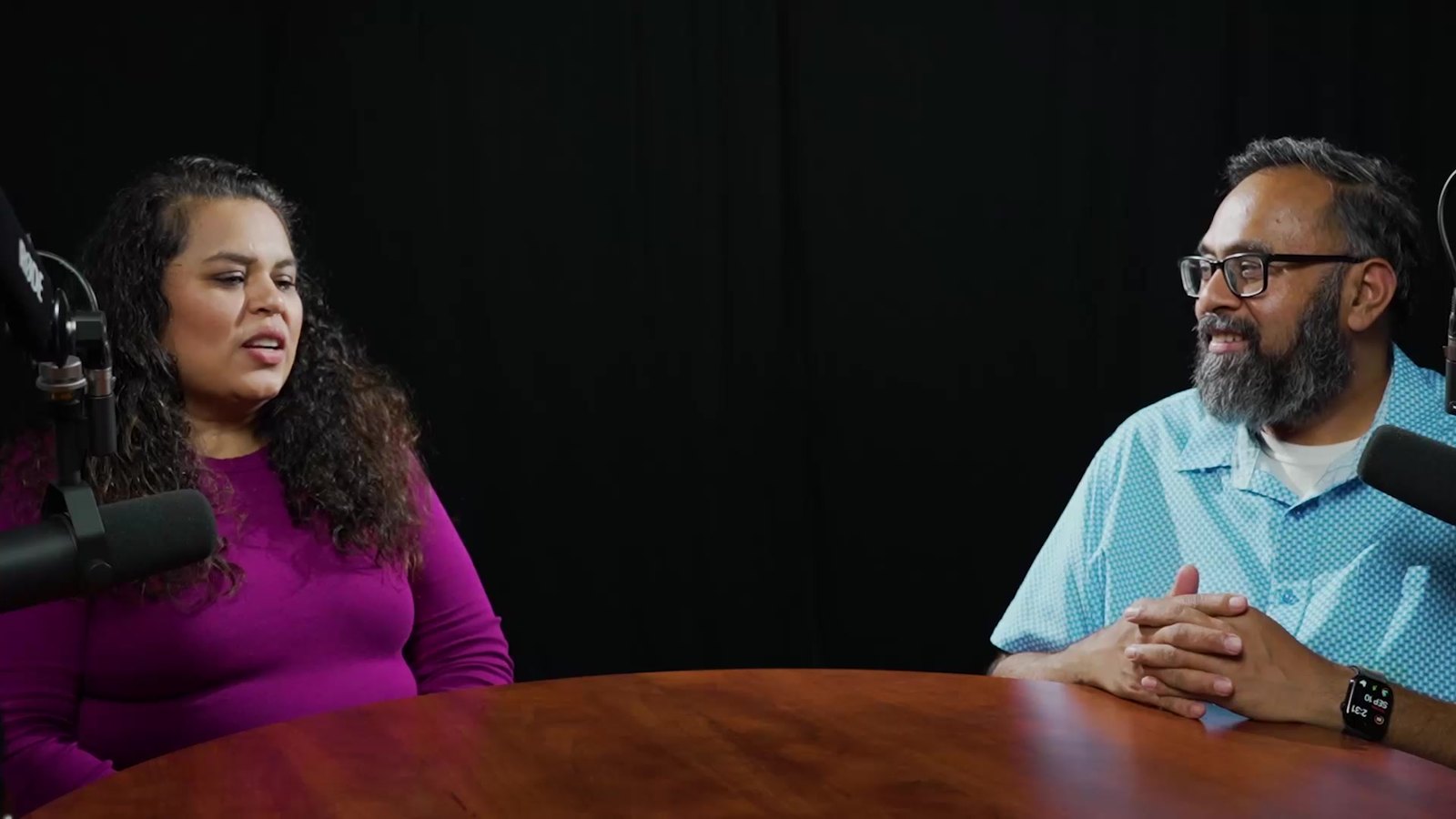 Two people recording at the podcast table in Studio 1801